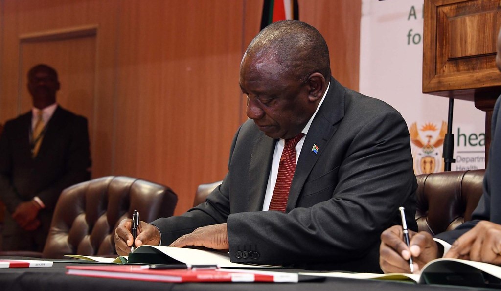 A photograph of South African president Cyril Ramaphosa signing a document.